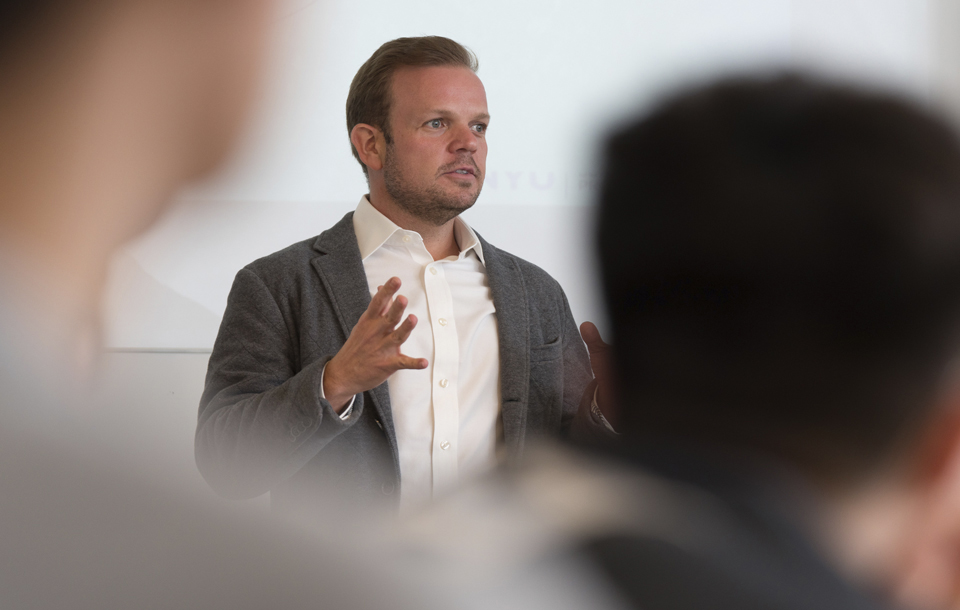 A professor in a suit gives a presentation to a class.