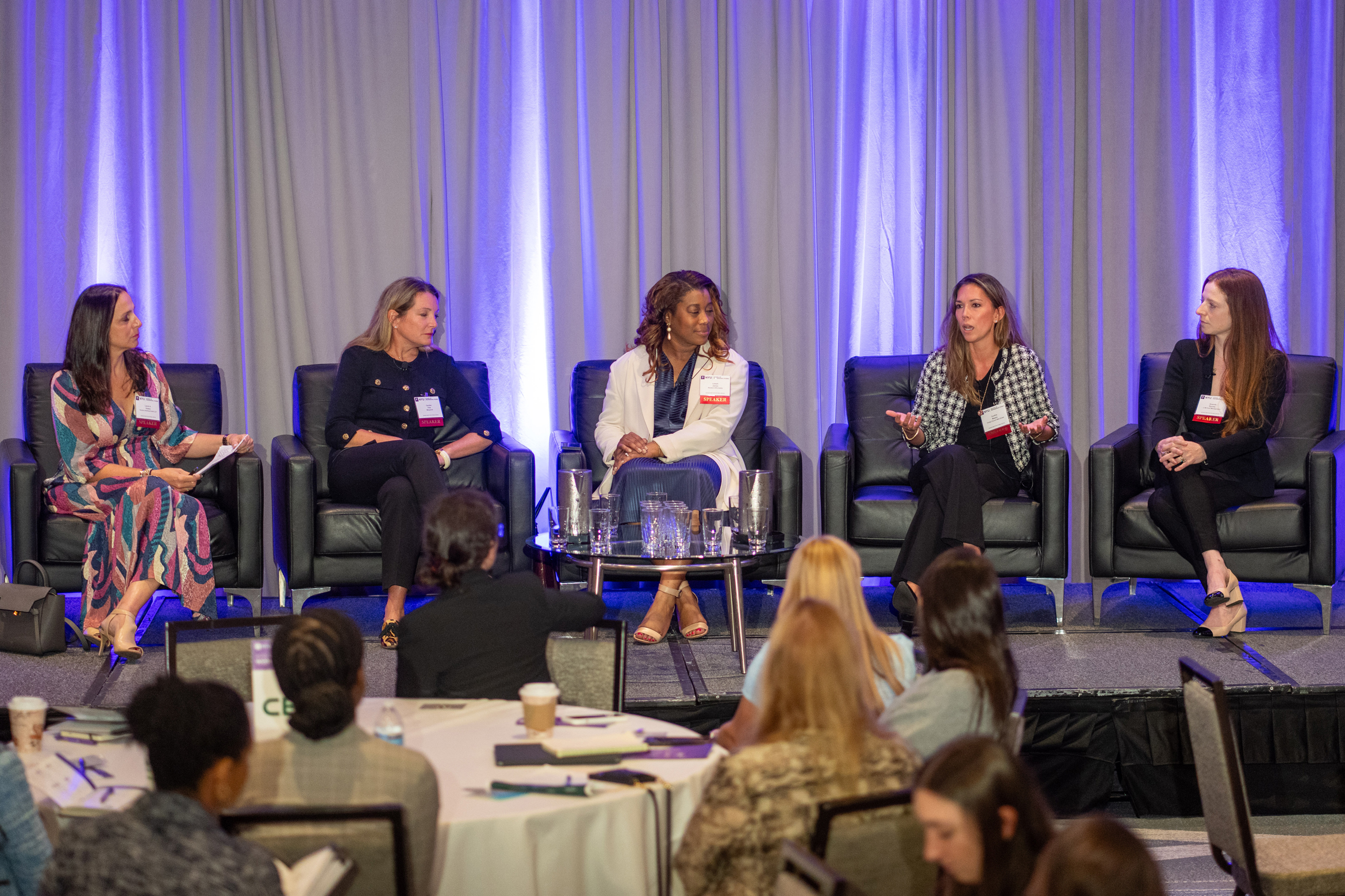 A ballroom full of real estate executives seated at round tables enjoy listening to a panel at the National Symposium of Women in Real Estate.