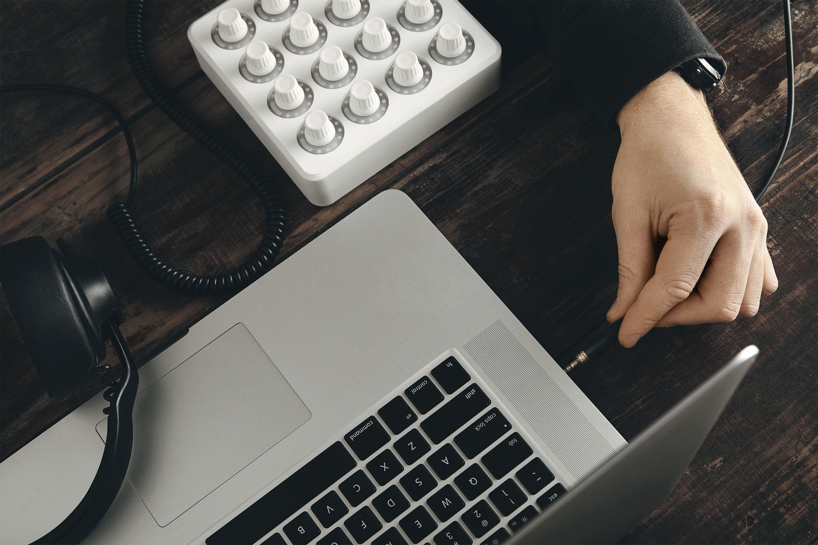 Hand connecting headphones to a laptop.