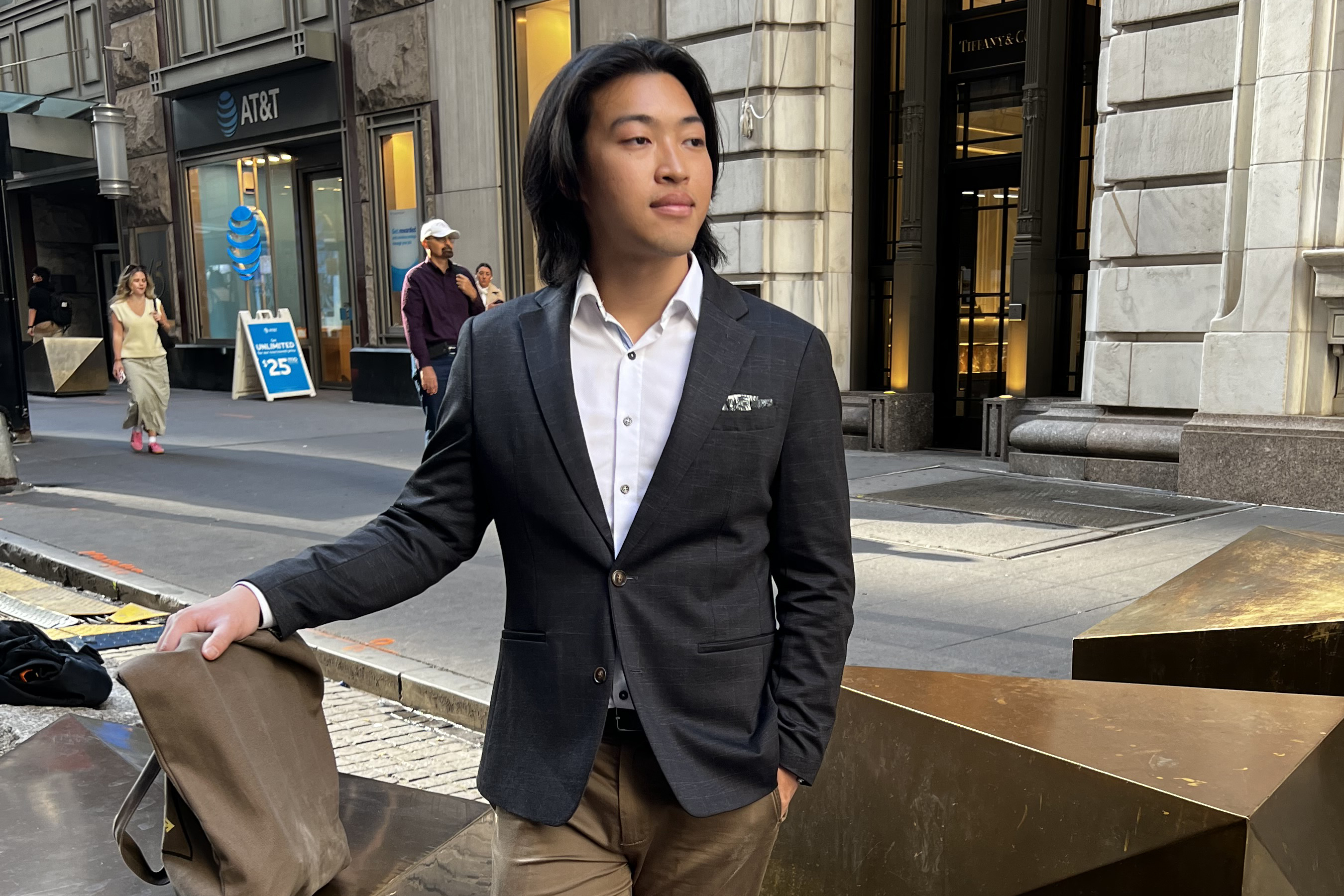 A sharp-dressed man strides through the bustling streets of NYC.