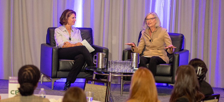 Two women engage in a dynamic discussion on stage at an NYU SPS National Symposium of Women in Real Estate (WiRE)