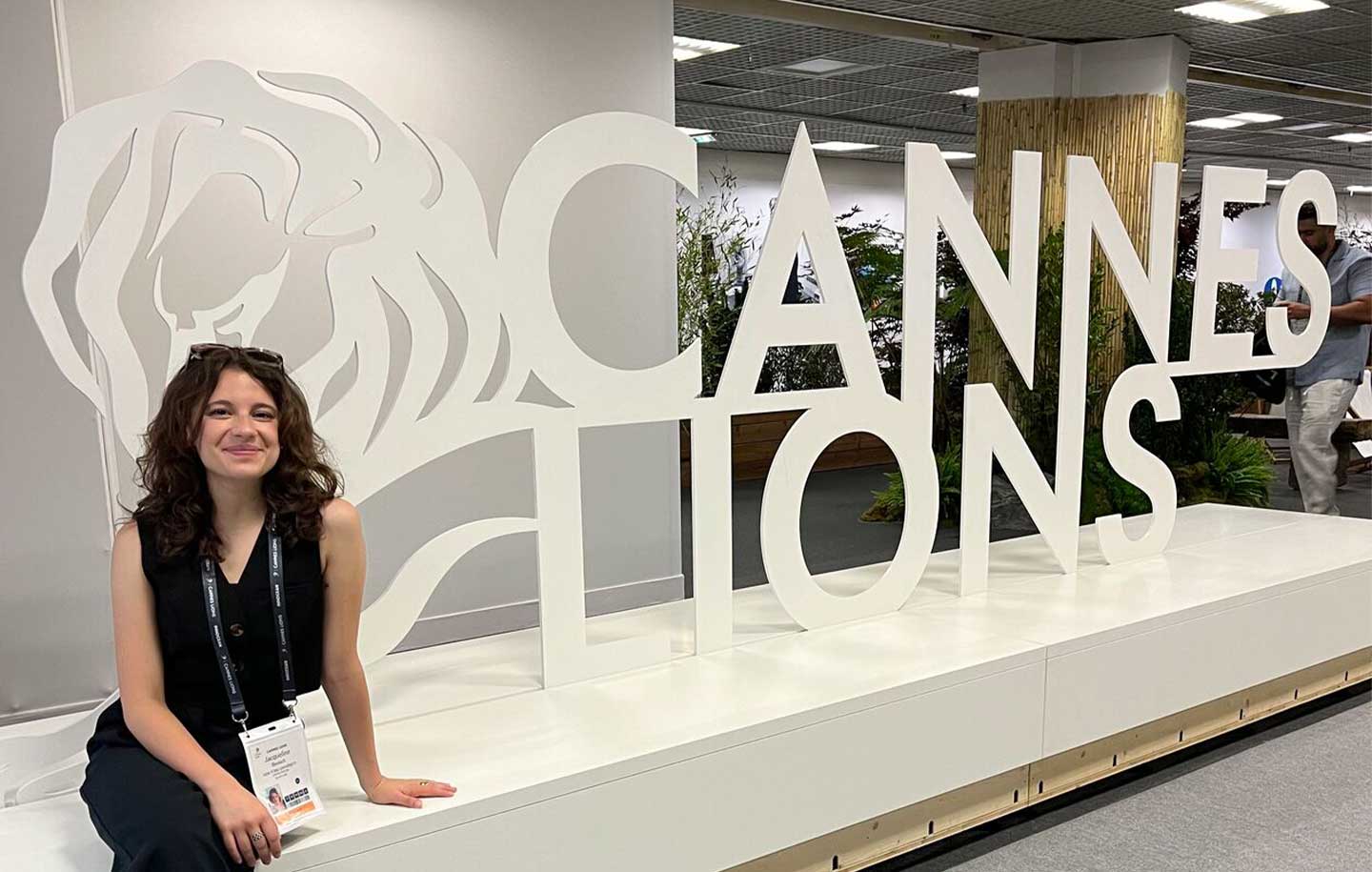 Smiling woman sits on a white platform beside large "Cannes Lions" letters.