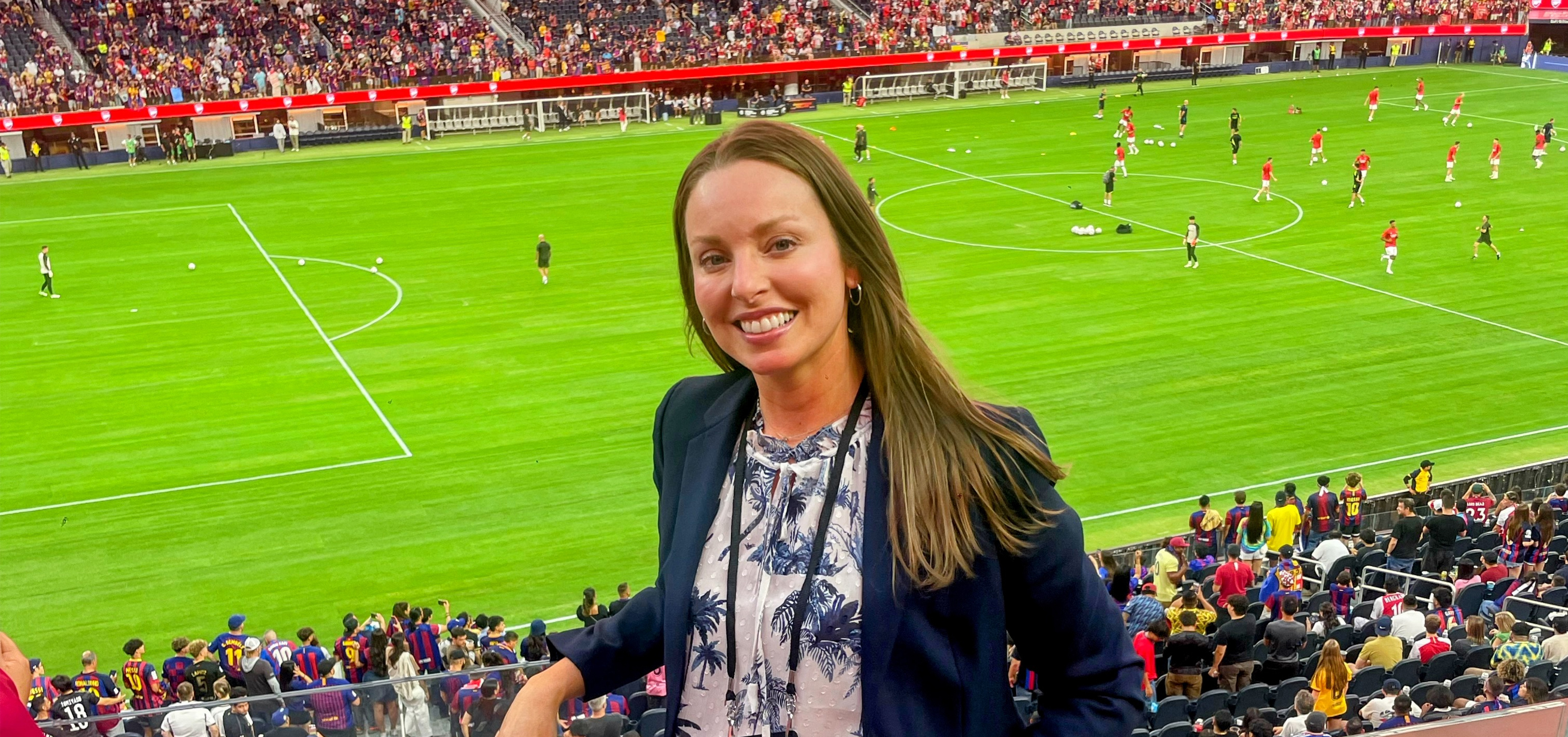 Sabrina Carrozza smiles for a photo with a soccer field in at SoFi Stadium while supporting FC Barcelona on their U.S. tour
