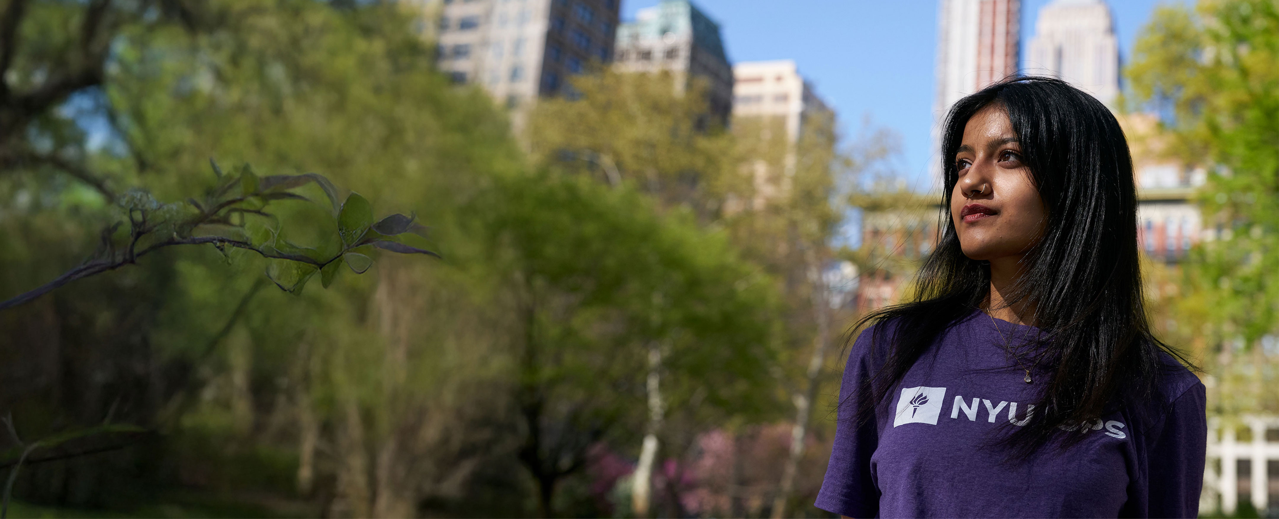 Student wearing an NYU SPS shirt stands outside.