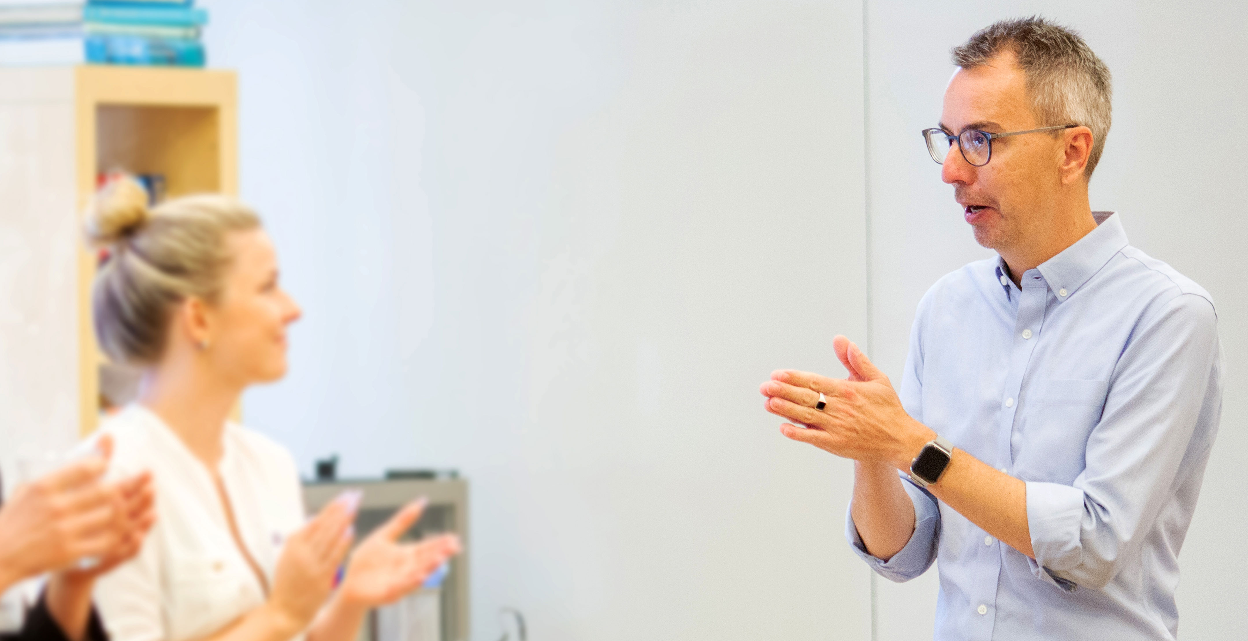 DAUS Associate Dean Douglas Harrison leads a team discussion in a classroom and colleagues clap for him